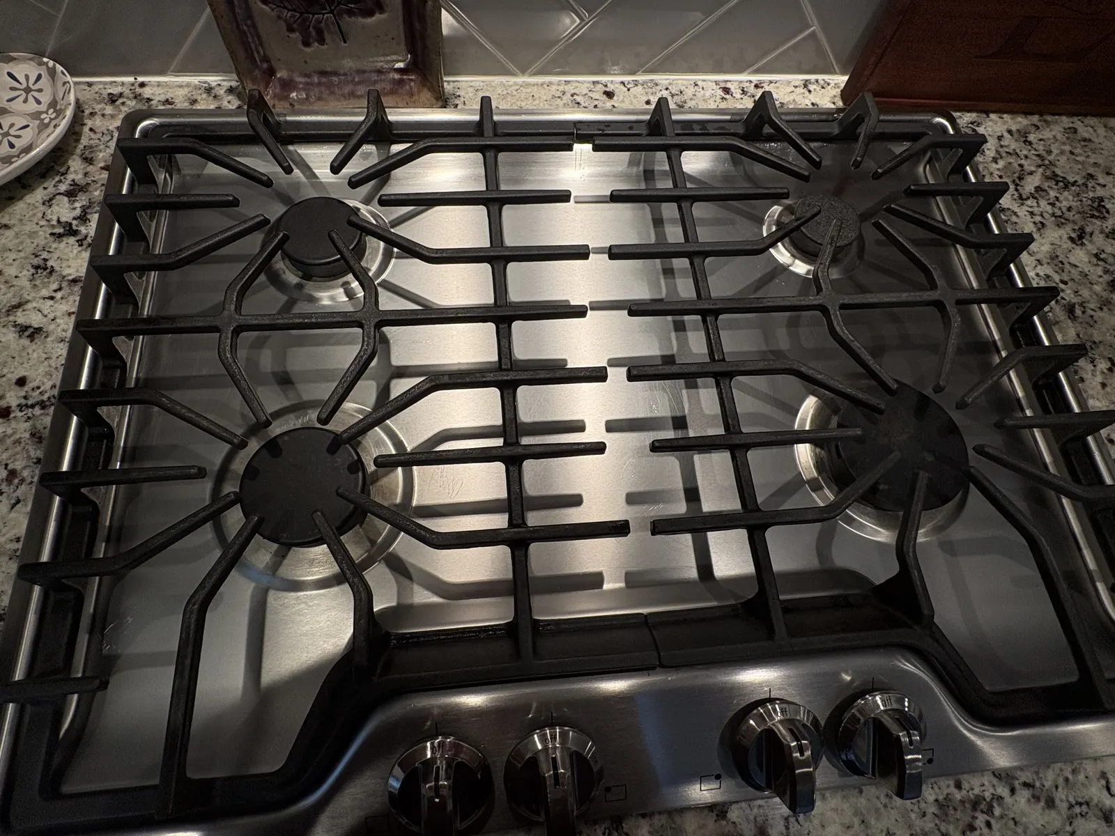Dirty stovetop burner grates before deep cleaning in a Raleigh, NC home